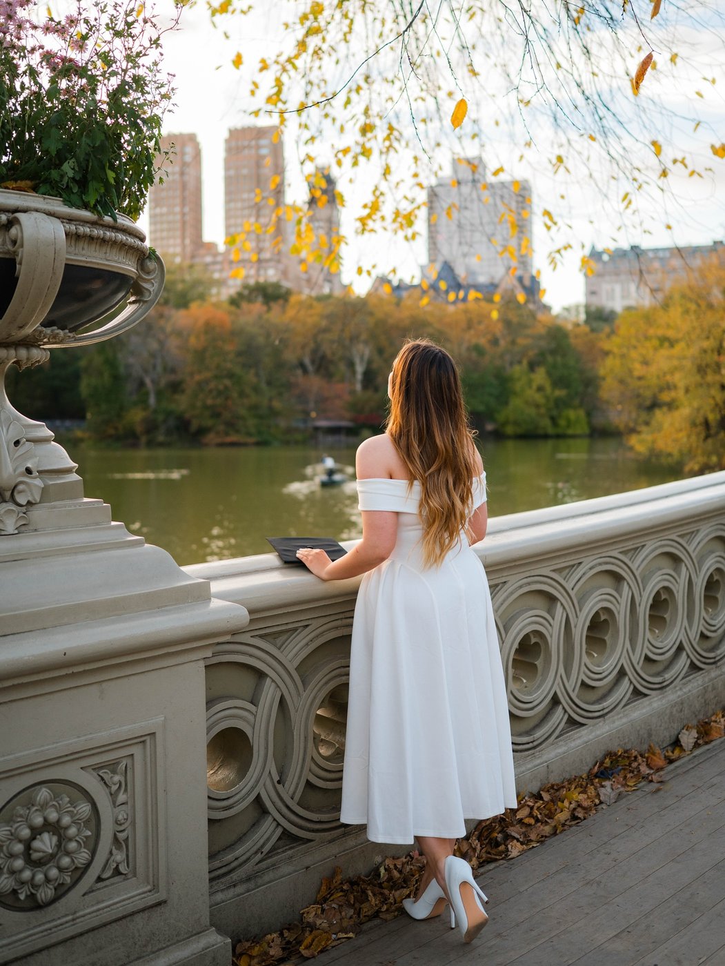 Person viewed from behind on Bow Bridge, with the lake and autumn trees in the background